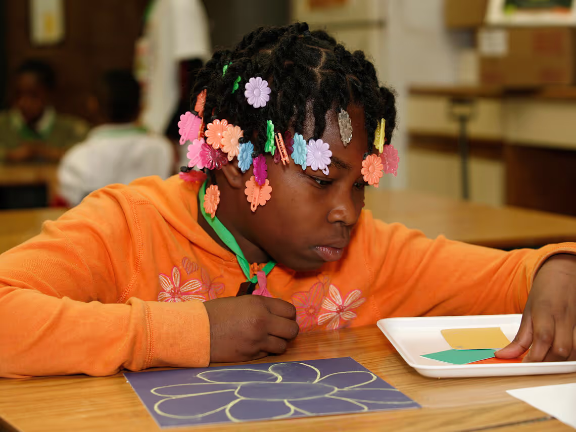 A little girl sitting at a table with a paper plate